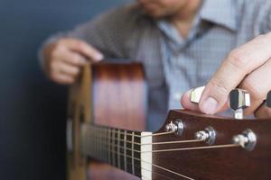 Mann, der Akustikgitarre stimmt foto