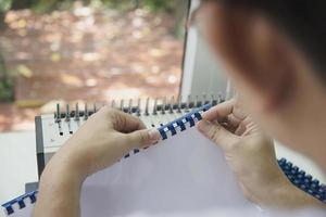 mann macht bericht mit kammbindemaschine - leute, die mit dem konzept stationärer werkzeuge arbeiten foto