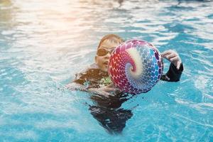 asiatisches glückliches kind, das im schwimmbad spielt foto