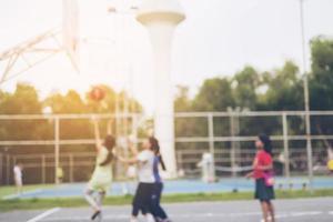 Verschwommenes Foto asiatischer Kinder spielt Basketball mit warmem Sonnenlicht von der oberen rechten Ecke