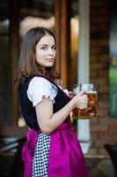 sexy russische frau im bayerischen kleid, das bierkrüge hält. foto