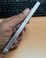 Ein graues Seitentelefon in der Hand eines Mannes. Es gibt einen Hintergrund für einen Schreibtisch und eine Tastatur für einen Computer. foto