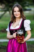 sexy russische frau im bayerischen kleid, das bierkrüge hält. foto