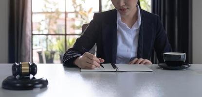 Geschäftsfrau und Anwälte diskutieren Vertragspapiere mit Messingwaage auf Holzschreibtisch im Büro. recht, juristische dienstleistungen, beratung, justiz und immobilienkonzept. foto