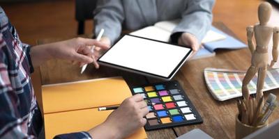 Zwei Künstler, die an einem Tablet arbeiten, färben den Papierton am Arbeitsplatz im Büro foto