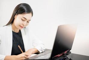 die asiatische geschäftsfrau freizeitkleidung mit laptop, der zu hause im wohnzimmer arbeitet. foto