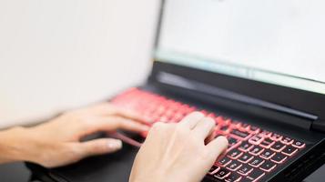 weibliche hand, die den laptop benutzt, während sie wegen der covid-epidemie zu hause bleiben, online-konferenz, schreibaufgaben. foto