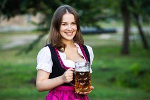 sexy russische frau im bayerischen kleid, das bierkrüge hält. foto