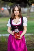 sexy russische frau im bayerischen kleid, das bierkrüge hält. foto