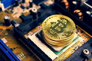 Stapel goldener Münzen mit Bitcoin-Symbol auf einem Mainboard. foto