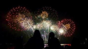 Menschen, die nachts gemeinsam ein wunderschönes Feuerwerk am Meer beobachten. foto