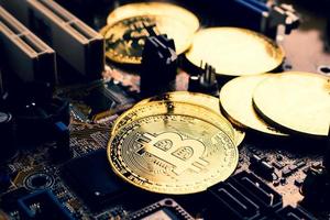 goldene Münzen mit Bitcoin-Symbol auf einem Mainboard. foto