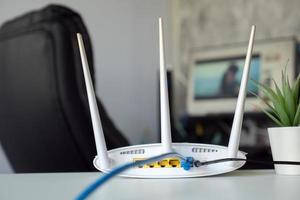 Nahaufnahme eines drahtlosen Routers auf dem Tisch zu Hause mit Desktop-Computer-Hintergrund foto
