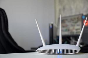 Nahaufnahme eines drahtlosen Routers auf dem Tisch zu Hause mit Desktop-Computer-Hintergrund foto