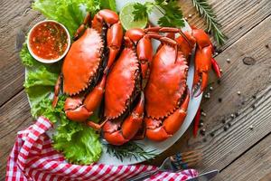 meeresfrüchteteller mit kräutern gewürzen rosmarin zitronensalat salatgemüse, frische krabben auf weißem teller und meeresfrüchtesoße, krabbenkochen gekochtes oder gedämpftes krabbenrot im restaurant - draufsicht foto