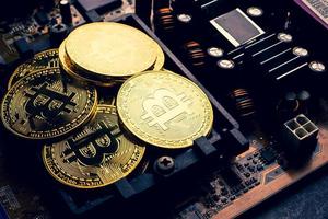 goldene Münzen mit Bitcoin-Symbol auf einem Mainboard. foto
