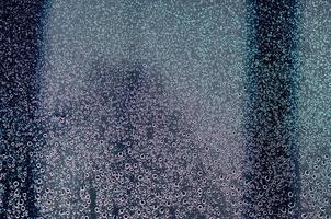 Fokus und verschwommenes Foto von Regentropfen auf Glasfenster mit dunkelblauer Farbe für abstraktes und Hintergrundkonzept.