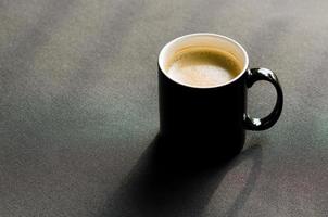 eine schwarze tasse heißen kaffee auf der balkoncouch mit schatten foto