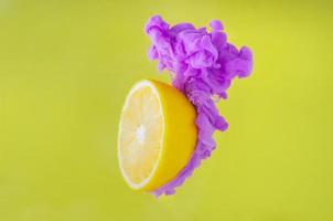 Zitronenscheibe mit teilweisem Fokus auf das Auflösen der violetten Plakatfarbe in Wasser foto