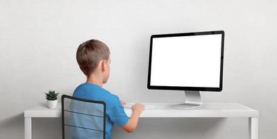 Junge, der am Computermodell arbeitet. isolierter anzeigebildschirm für die werbung von webseiten. Rückansicht von Boz und Arbeitstisch foto