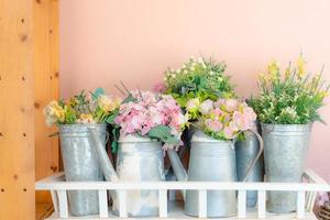 Bunte Rosenblüten im Topf mit rosafarbenen Wandhintergründen foto