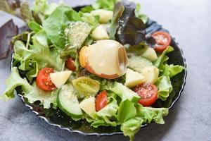 gesunder salat gemüseblätter mischen salat mit obst und frischem salat tomatengurke und gekochtem ei auf dem teller auf dem tisch frisches essen foto
