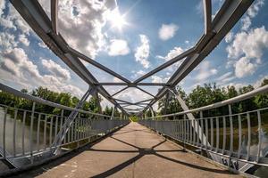 Eisenstahlrahmenkonstruktion der Fußgängerbrücke über den Fluss. Weitwinkelansicht foto