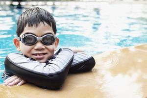 asiatisches glückliches kind, das im schwimmbad spielt foto