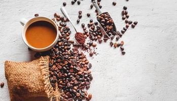 Draufsicht auf eine Kaffeetasse und Kaffeepulver auf einem Holzlöffel auf weißem Hintergrund. kaffeebohnen in der edelstahlschaufel. flach liegen und kopierraum. foto