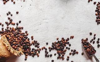 Flache Lage von Kaffeebohnen im braunen Sack auf weißem Hintergrund. kaffeebohnen in der scoop.draufsicht aus edelstahl und kopierraum. foto
