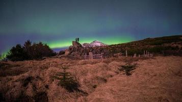 tourist, der die aurora borealis über den sternenklaren nachthimmel in island schaut. das Nordlicht, eines von mehreren astronomischen Phänomenen, die Polarlichter genannt werden. foto