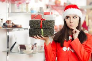 neugieriges Weihnachtsmädchen mit Geschenken im Geschenkeladen foto