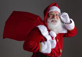 weihnachtsmann mit brille schaut in die kamera und lächelt, auf grauem hintergrund foto