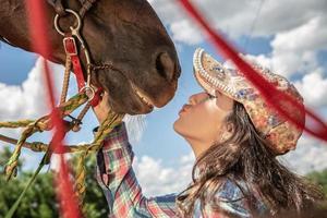 schönes Brunettemädchen, das ihr Pferd küsst foto