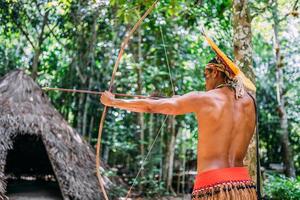 Indianer vom Pataxo-Stamm mit Pfeil und Bogen. brasilianischer Indianer mit Federschmuck und Halskette foto