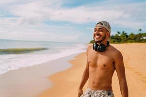 sommerferien, technologie- und internetkonzept. lächelnder lateinamerikanischer Mann mit Headset und Mütze foto