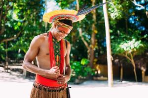 indianer vom pataxo-stamm mit gefiedertem kopfschmuck, der nach unten schaut und lächelt. einheimisch aus brasilien mit traditioneller gesichtsbemalung. foto