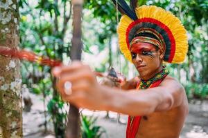 Indianer vom Pataxo-Stamm mit Pfeil und Bogen. brasilianischer Indianer mit Federschmuck und Halskette foto