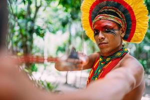 Indianer vom Pataxo-Stamm mit Pfeil und Bogen. brasilianischer Indianer mit Federschmuck und Halskette foto