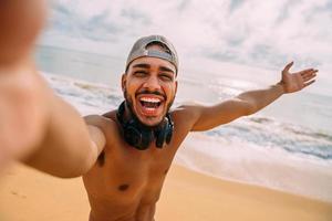 freundlicher junger lateinamerikanischer mann, der einlädt, nach brasilien zu kommen, selbstbewusst und lächelnd, eine geste mit der hand machend, positiv und freundlich foto