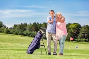 Seniorenpaar gibt Daumen hoch auf einem Golfplatz. foto
