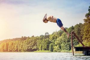 junger fitter Mann, der in einen See springt foto