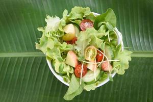 salatgemüse - salatschüssel mit obst und frischem salat tomatengurke auf bananenblatt gesundes essen konzept foto