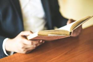 Geschäftsmann oder Student, der ein Buch zur Hand hält - Business Education Study Concept Mann liest Buch auf dem Tisch foto