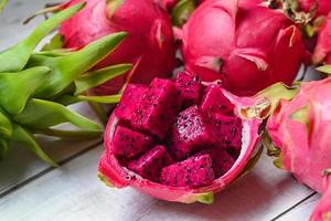 drachenfruchtscheibe auf fruchtschale mit pitahaya-hintergrund, frische rote lila drachenfrucht tropisch im asiatischen thailand gesundes fruchtkonzept foto