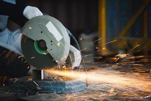 Schneiden eines Stahls mit Funkenspritzern, Metallbearbeitung mit Winkelschleifer. Funken in der Metallbearbeitung. foto