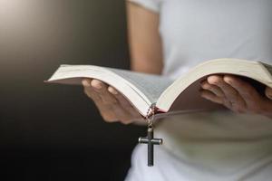 frau, die morgens auf der heiligen bibel betet. frauenhand mit betender bibel. foto