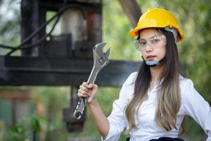 porträt eines schönen asiatischen ingenieurs, der einen schraubenschlüssel hält, der hintergrund ist ein container, ein konzept eines ingenieurs oder eines industriemechanikers. foto