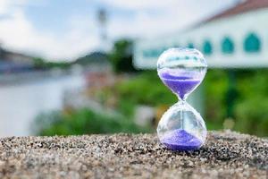 kunstzusammenfassung die sanduhr stand auf der rauen felsenoberfläche nahe dem flutkanal. es zeigt, dass das fließende Wasser niemals zurückfließt. Zeit auch foto