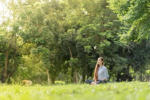 glückliche frau, die meditiert und sich im park entspannt. Meditieren in der Natur. konzept für gesunden lebensstil und entspannung. foto